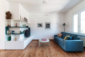 A modern living room with a sofa, coffee table, and shelves with decorative items.