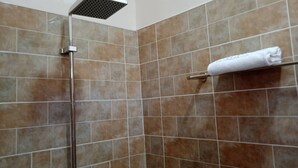 Doccia con soffione flessibile e porta asciugamani con asciugamano piegato.