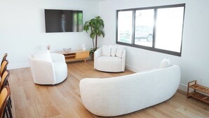 A modern living room with a large window, a flat-screen TV, and a wooden floor. - Casita Canal  (Naples)