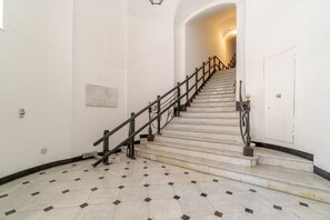 Una escalera de mármol con barandillas negras que conduce a una puerta.
