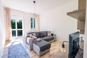 A modern living room with a sofa, a fireplace, and a large window with curtains.