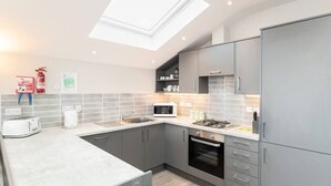 A modern kitchen with grey cabinets, a microwave, a toaster, and a gas stove. - Seaside 3BD Retreat with Balcony and Stunning Views (Westward Ho!)