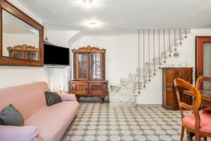En stue med sofa, et træskab, en stol og en trappe med hængende pynt.