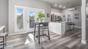Una cocina moderna con una isla central, muebles blancos y electrodomésticos de acero inoxidable.
