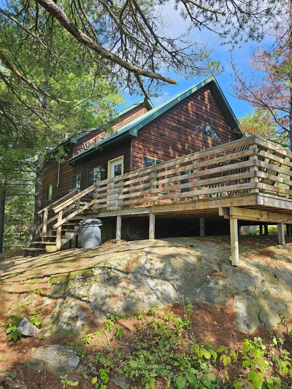 A rustic cabin with a wooden deck and stairs leading to the entrance.