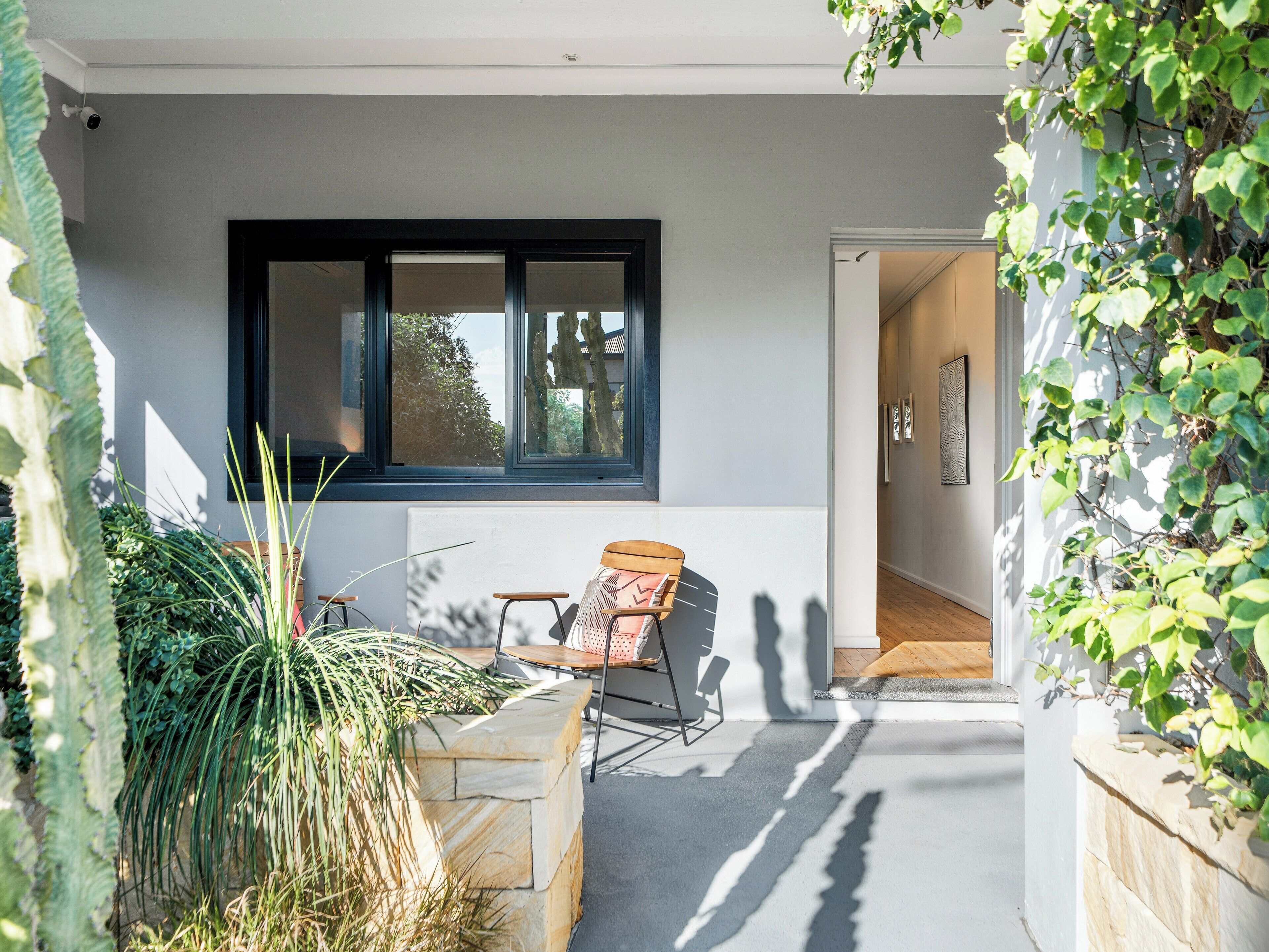 A modern outdoor seating area with a stone planter, a wooden chair, and a table.