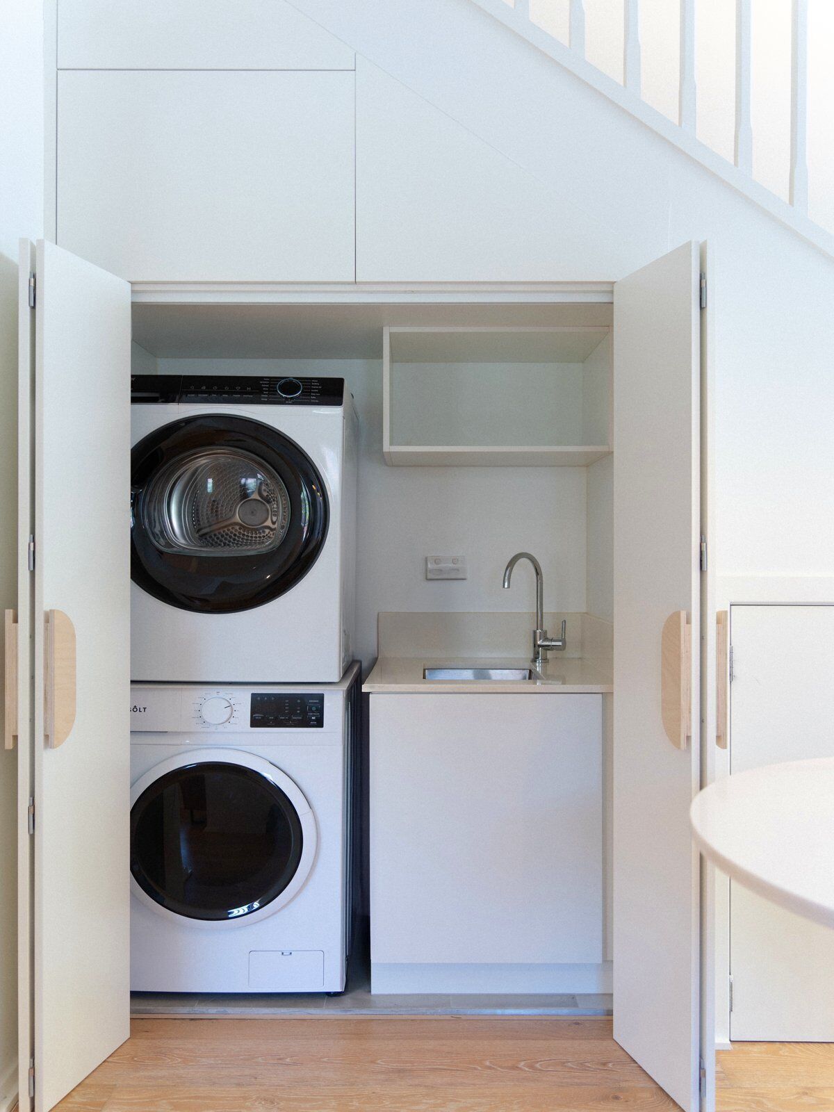 A compact laundry room with a washing machine, dryer, and sink.