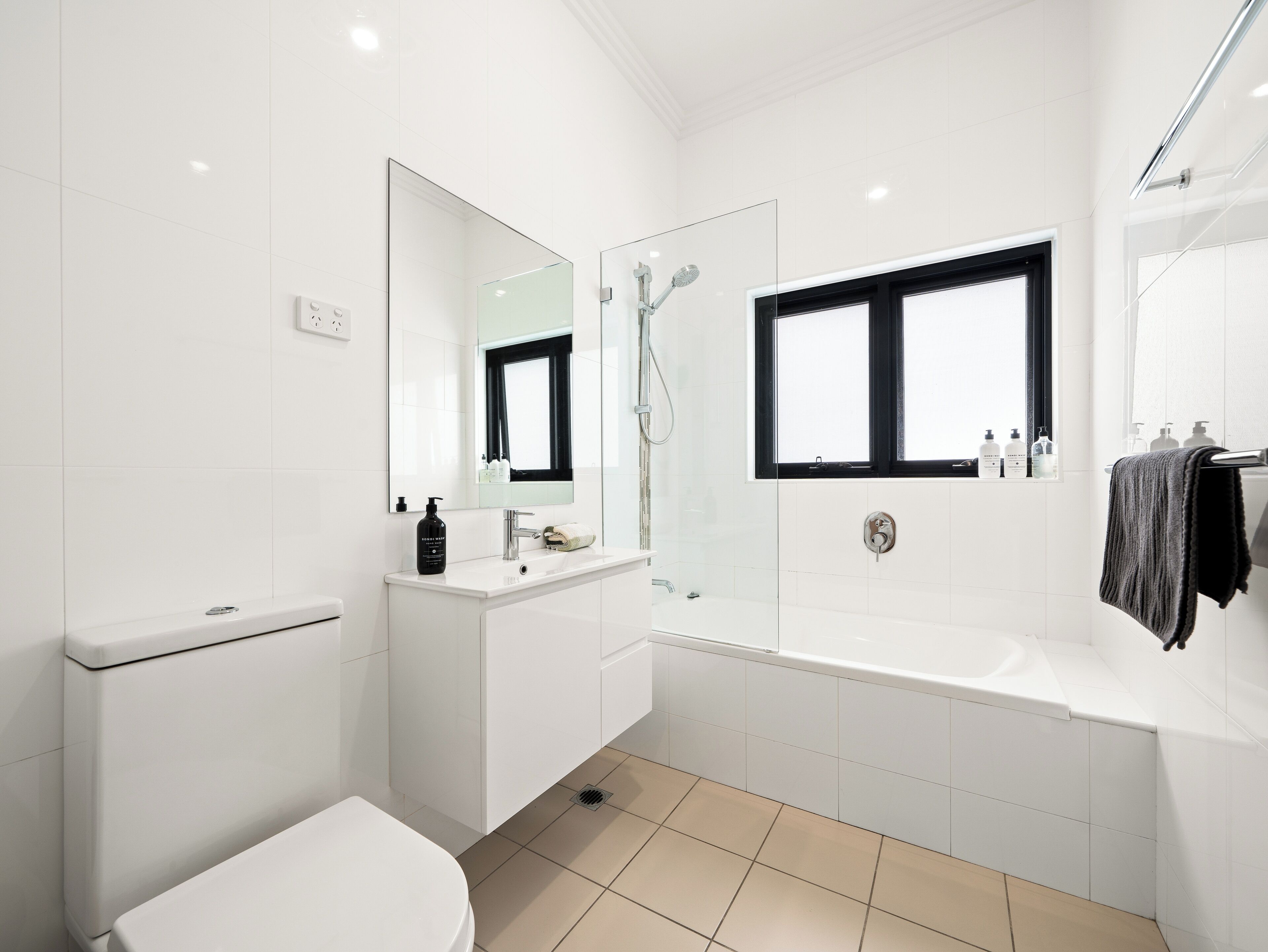 A modern bathroom with a toilet, sink, mirror, shower, and bathtub.