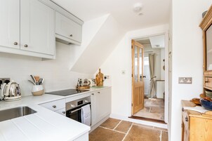Una cocina moderna con armarios blancos, horno empotrado y una encimera con hervidor y utensilios.