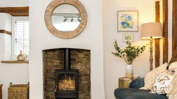 A cozy living room with a stone fireplace, a round mirror, a blue sofa, and a lamp on a side table.