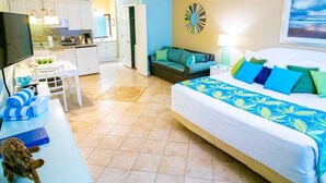 A hotel room with a bed, a desk, a TV, a kitchenette, and a bathroom.