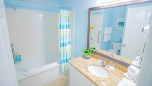 A bathroom with a shower, a sink, a mirror, and a towel rack.