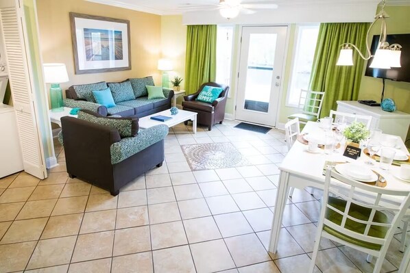 A living room with a sofa, coffee table, and dining table set up.