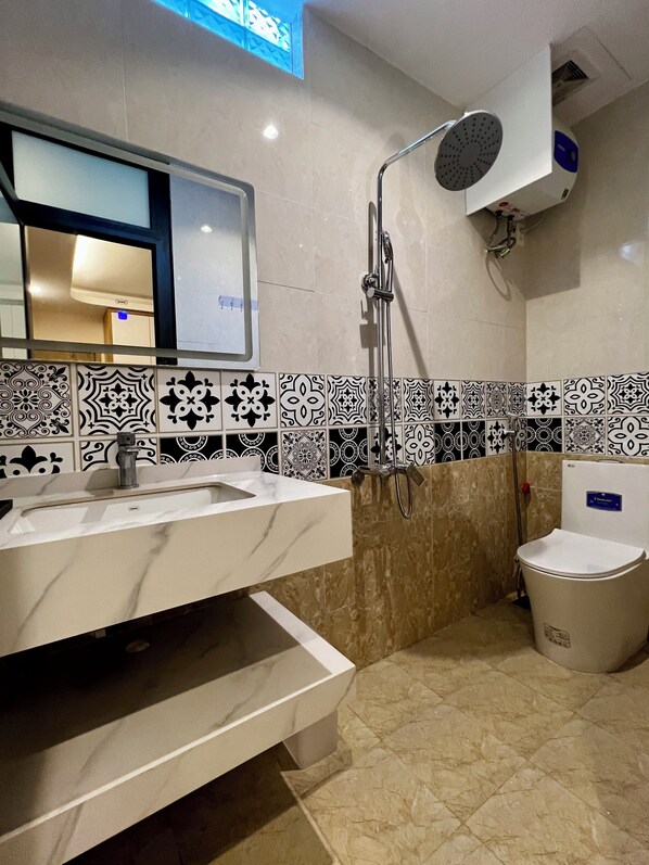 A modern bathroom with a marble sink, a shower with a handheld showerhead, and a toilet. - The Urban Quarter Hanoi (Hanoi)