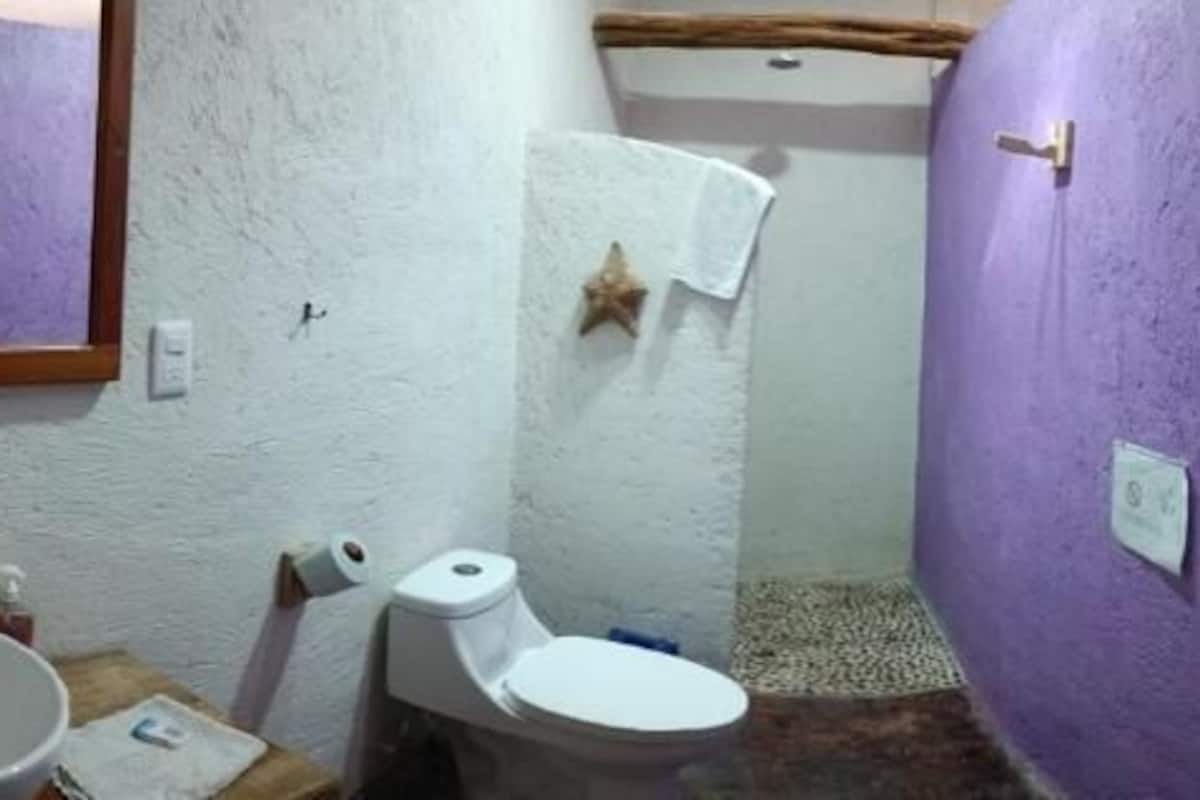 Un baño con un lavamanos blanco, un inodoro y una pared morada.