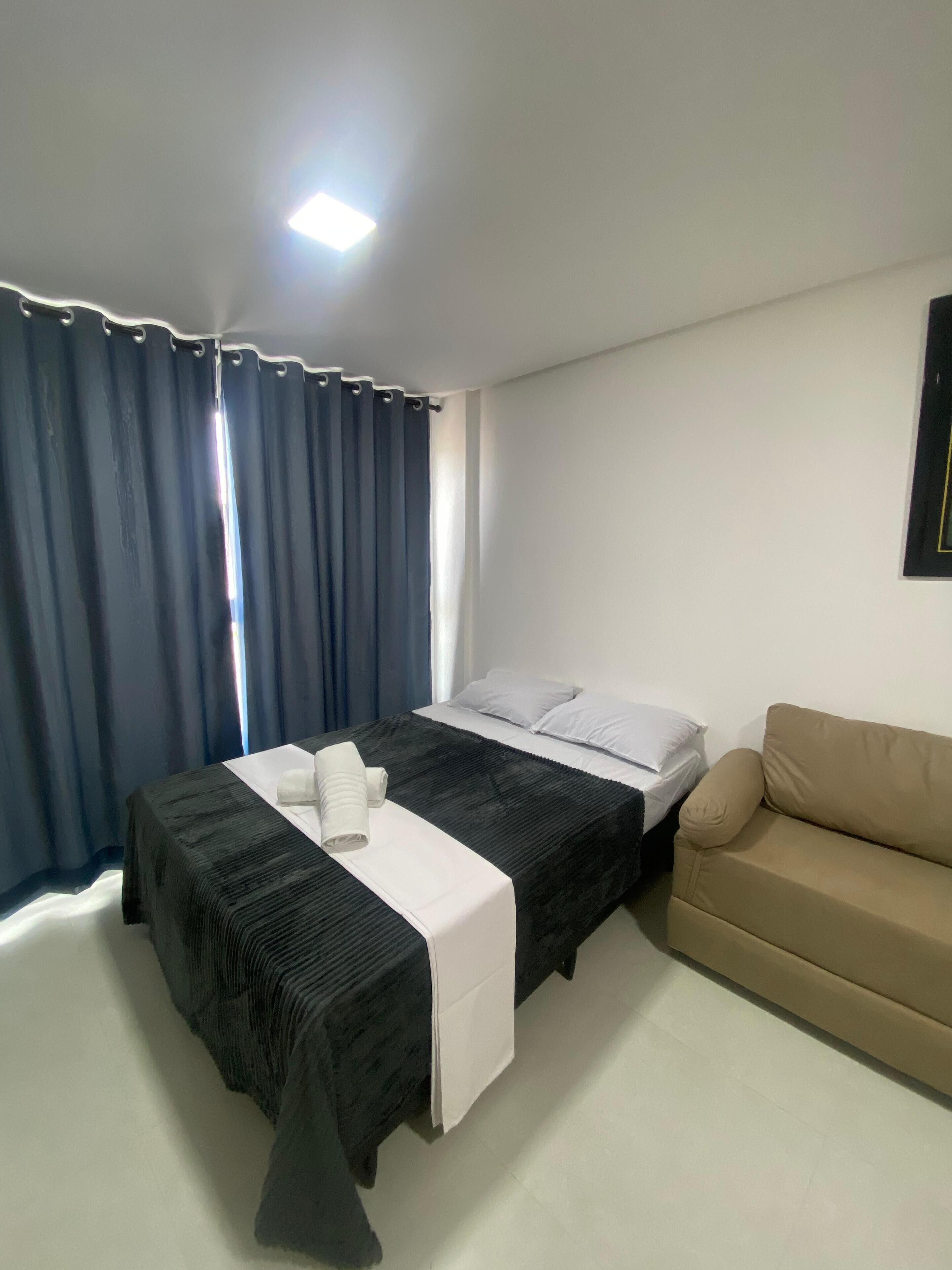 Een slaapkamer met een bed, een bank en een raam met gordijnen.