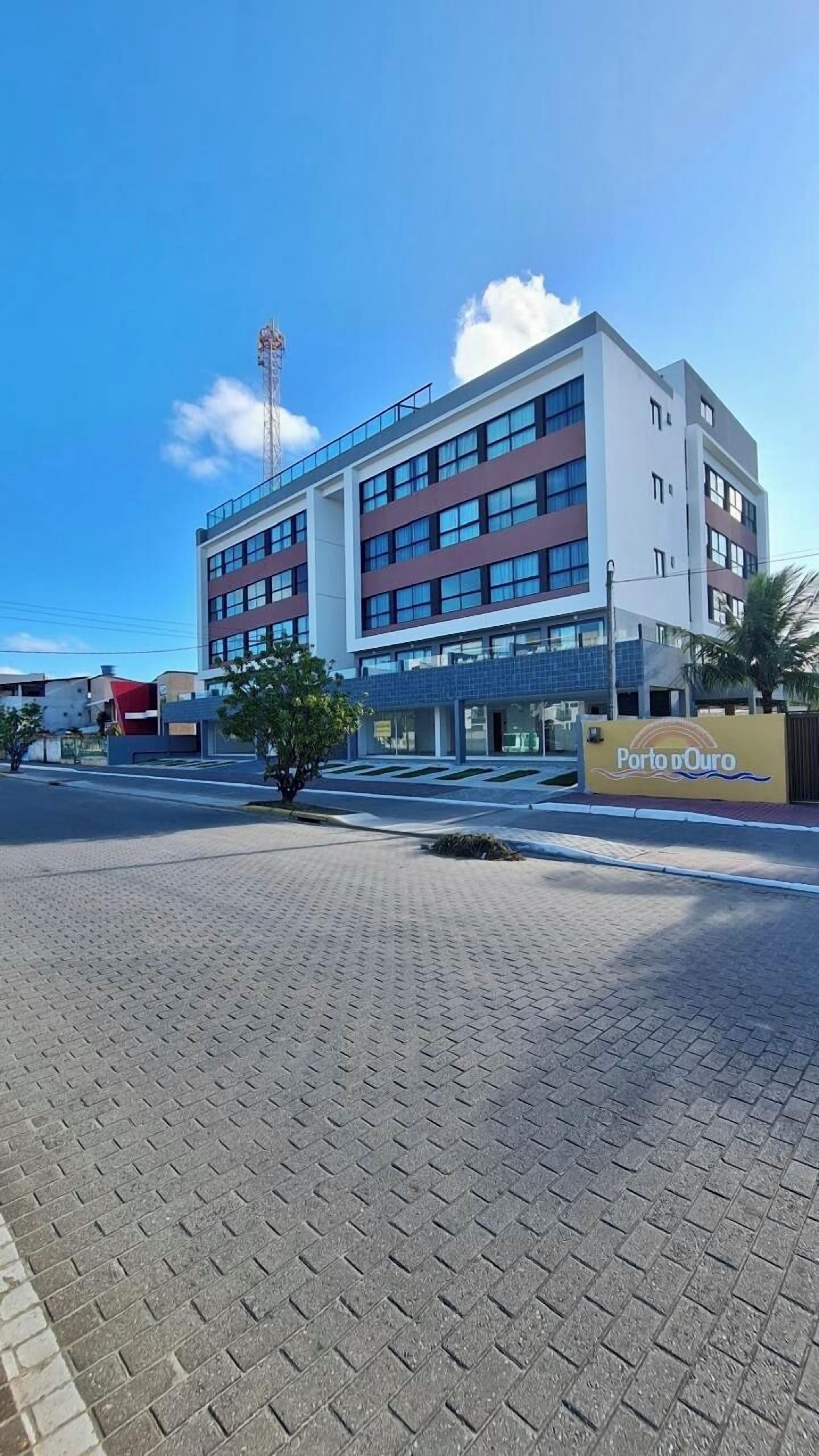Un hotel moderno con tetto piatto, diversi piani e un cartello ben visibile con la scritta "Porto do Ouro".