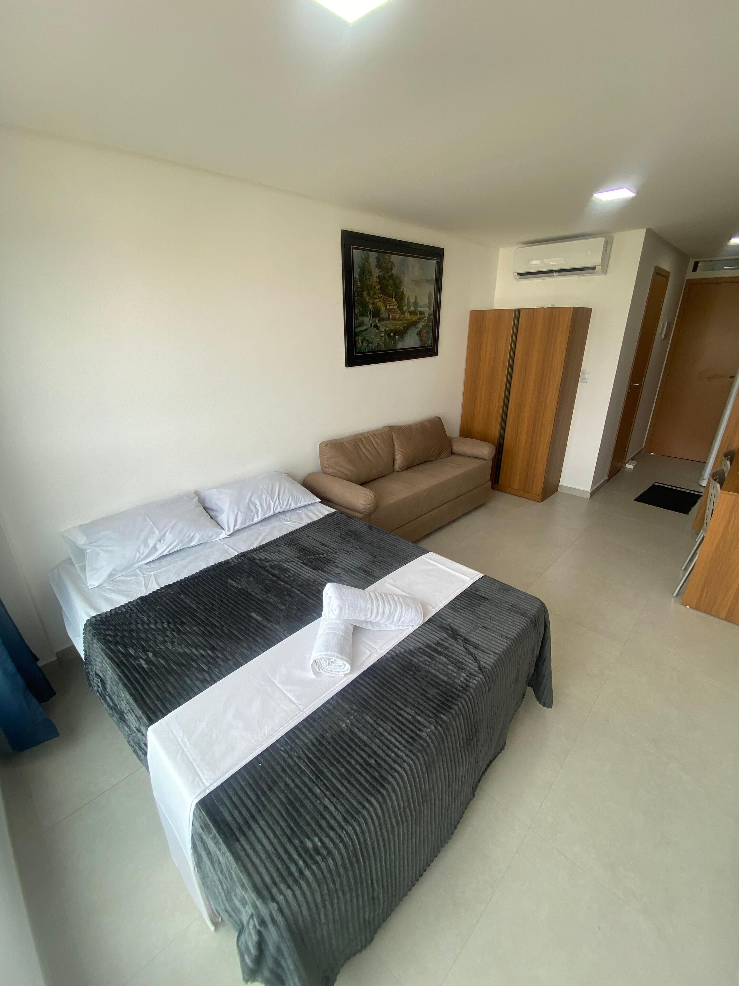 Ein Schlafzimmer mit Bett, Sofa, einem Wandbild und einer Klimaanlage.