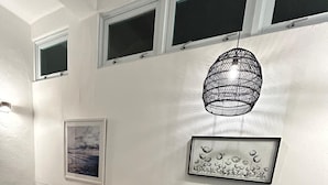 Una sala de estar moderna con un sofá negro, sillas grises, una mesa de comedor y una lámpara colgante.