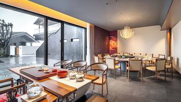 Un espace repas moderne avec une grande table dressée pour un repas, entourée de chaises.