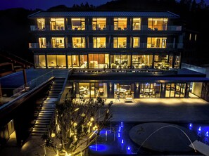 Um edifício com vários andares, piscina e iluminação externa.