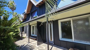 A modern house with a stone patio, large windows, and a wooden deck. - Tree Story Pension (Seogwipo)