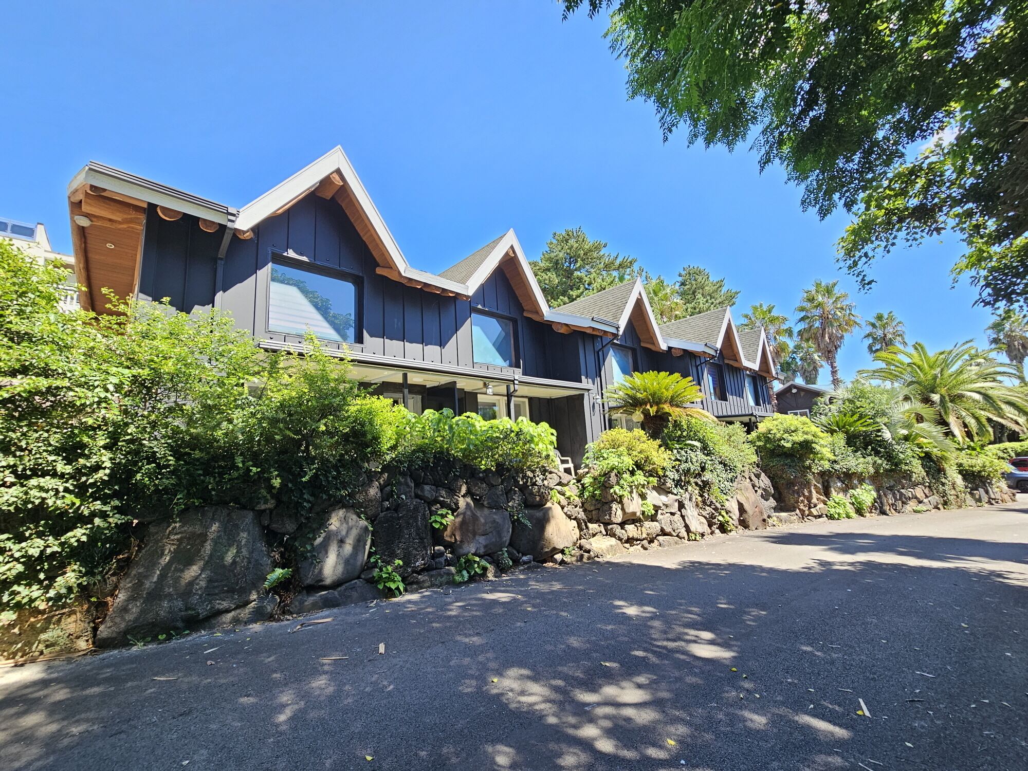 A row of modern, dark-colored cabins with large windows and a stone retaining wall.