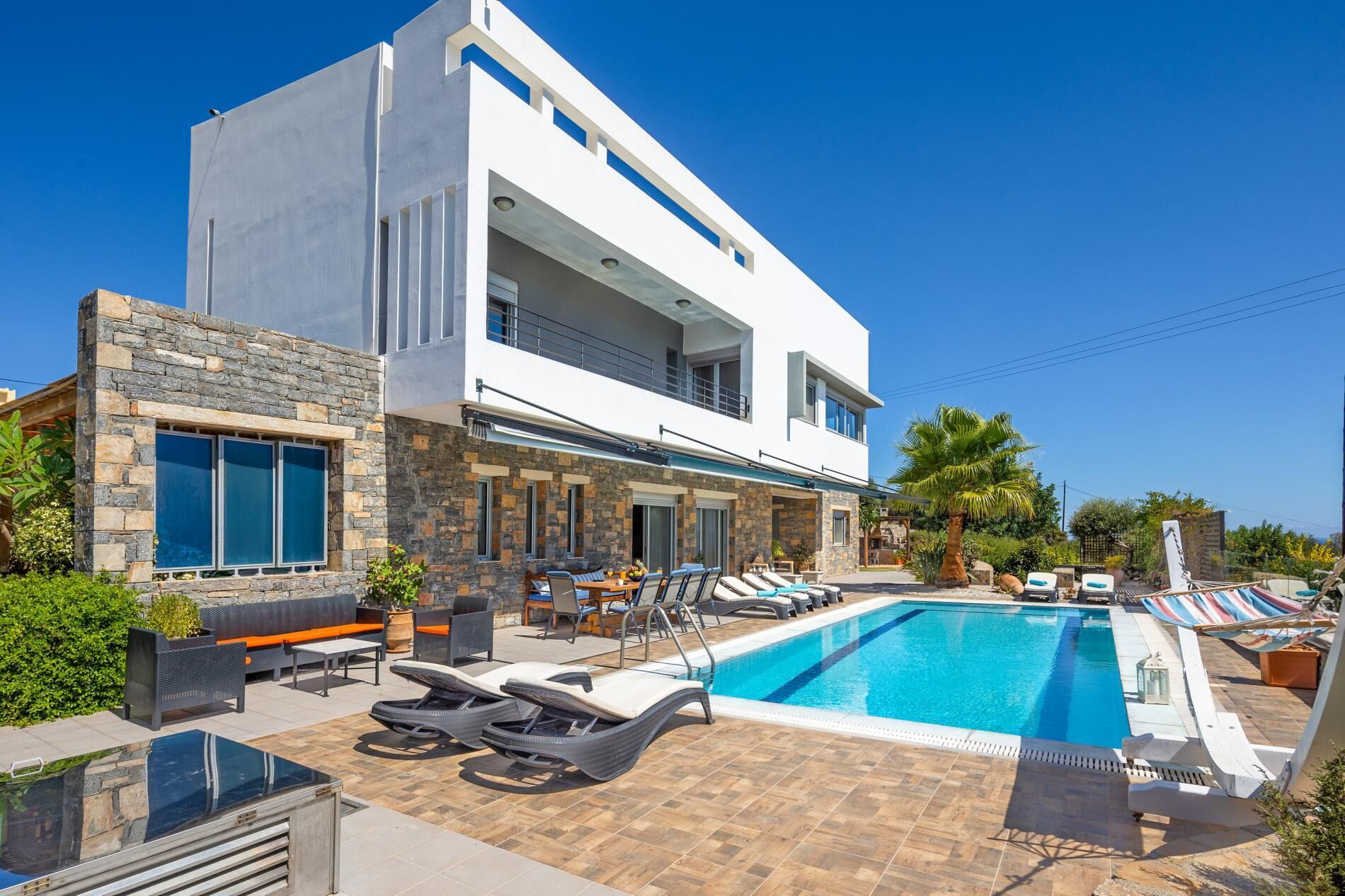 Ein modernes, zweistöckiges Gebäude mit Pool, Außenbereich und einer Fassade aus Stein.