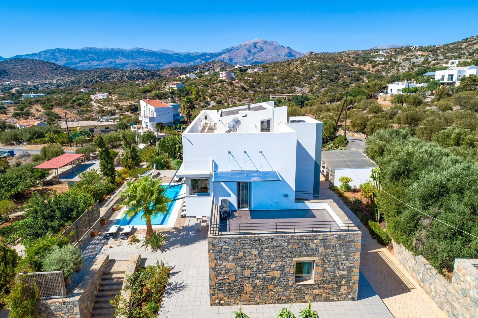 Eine moderne Villa mit Swimmingpool, Steinwänden und Blick auf die umliegenden Hügel.