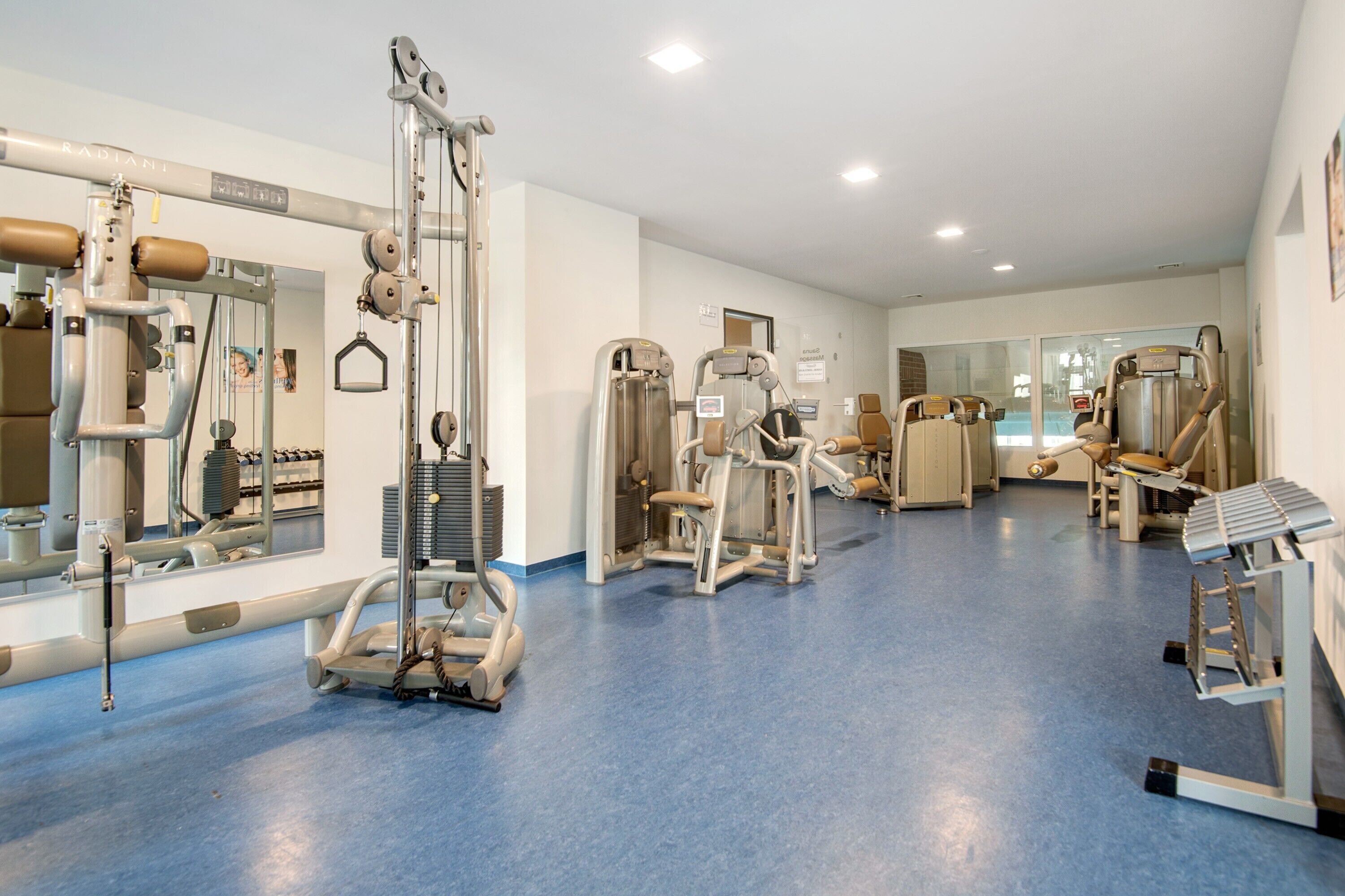 A gym with exercise equipment, mirrors, and a blue floor.