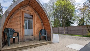 Eine Holzhütte mit einer Tür, zwei Stühlen und einer Bank vor der Tür.