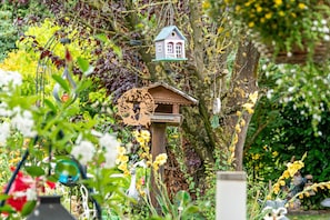 A birdhouse on a tree, surrounded by greenery and flowers. - Apartment 'Ferienwohnung Haus Helene' with Shared Terrace, Shared Garden and Wi-Fi (Zetel)