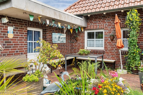 A brick house with a patio, a table, and various plants.