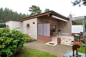 Un edificio rústico con fachada de ladrillo, un patio cubierto con mobiliario exterior y una escultura decorativa de toro en primer plano.