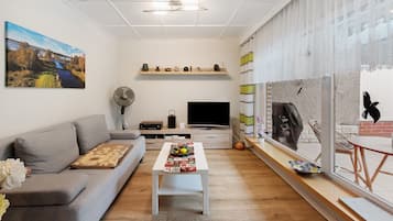 A modern living room with a sofa, coffee table, TV, and artwork on the walls.