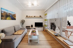 Una sala de estar moderna con un sofá, una mesa de centro, un televisor y obras de arte en las paredes.