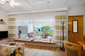 A modern living room with a television, a coffee table, and a view of the outdoor garden.