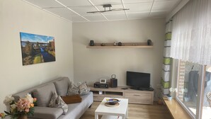 Ein modernes Wohnzimmer mit einer Couch, einem Couchtisch, einem Fernseher und Dekorationselementen.