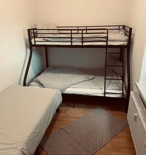 Une chambre avec un lit superposé, un matelas sur le lit du bas et un lit simple sur le lit du haut.