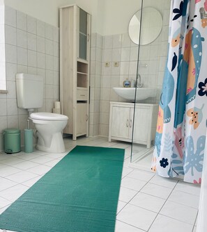 Une salle de bain avec des toilettes, un lavabo, un meuble et un tapis vert.
