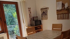 Comedor con mesa, sillas, televisor y vista a zonas verdes.