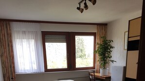 Un dormitorio con cama, escritorio, silla, planta en maceta y armario.