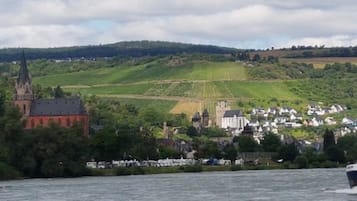 Ein Fluss mit einem Boot, einer Kirche und einer Stadt am gegenüberliegenden Ufer.