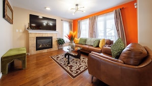 A living room with a fireplace, a sofa, a coffee table, and a television. - Celest Homes! Spacious, family home, right  for your next family adventure.  (Edmonton)
