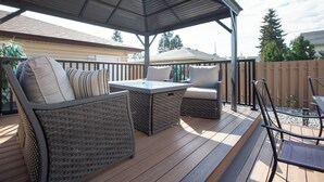 An outdoor patio with wicker furniture, a table, and a covered seating area. - Celest Homes! Spacious, family home, right  for your next family adventure.  (Edmonton)