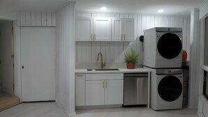 A compact kitchen with white cabinetry, a stainless steel dishwasher, a built-in oven, and a potted plant. - NEWLY LISTED: Secluded Tree House Hideaway 2-bedroom duplex in Honolulu! (Millilani)