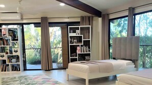 A modern bedroom with a large bed, a smaller bed, a TV, and a bookshelf. - NEWLY LISTED: Secluded Tree House Hideaway 2-bedroom duplex in Honolulu! (Millilani)