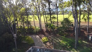 A view of a property with a pathway leading to a grassy field, surrounded by trees and a fence. - NEWLY LISTED: Secluded Tree House Hideaway 2-bedroom duplex in Honolulu! (Millilani)