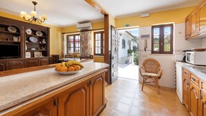 A kitchen with wooden cabinets, a marble countertop, and a bowl of fruit.