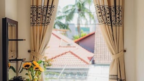 A room with a view of a red-roofed building and a palm tree outside.
